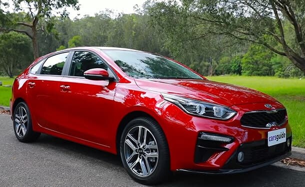 سياره-كيا-هاتشباك-سيراتو-2019-احمر-سيده-اشجار-حديقه